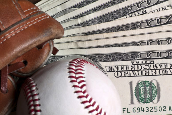 Baseball ball, glove and money on wooden table