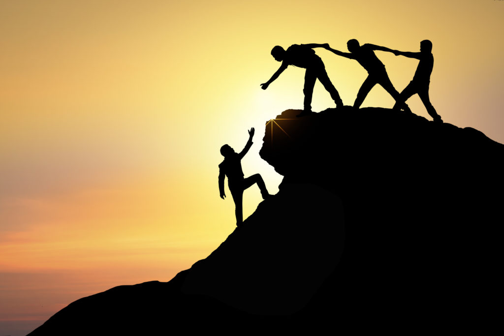 Assistance, teamwork and achievement concept. silhouette of man helping friend climbing rock to top and success together