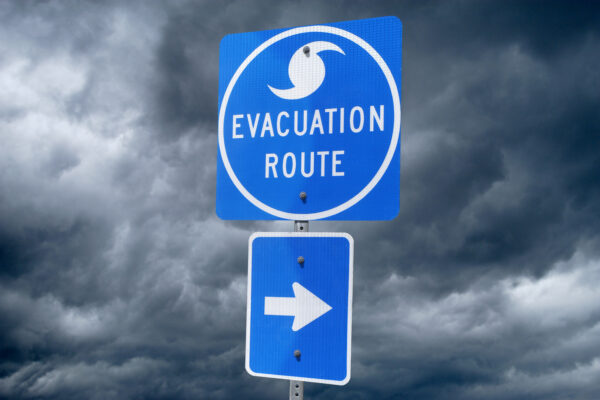 A Directional Sign in Front of Storm Clouds indicating the Storm Evacuation Route. Arrow on sign is directing to the right.